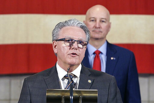 Nebraska Speaker of the Legislature, Jim Scheer of Norfolk, speaks during a press briefing with Neb. Gov. Pete Ricketts behind him, in Lincoln, Neb., Wednesday, March 25, 2020. Nebraska approved an $83.6 million emergency relief package Wednesday to help public health officials respond to new coronavirus as the number of cases continued to rise and Gov. Pete Ricketts expanded the list of counties where restaurants and bars will be forced to close their dining areas. (AP Photo/Nati Harnik)