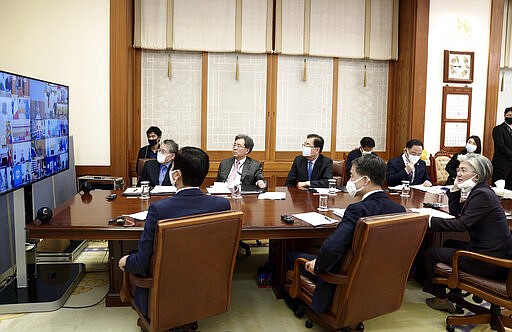 In this photo provided by South Korea Presidential Blue House via Yonhap News Agency, Presidential staffs watch a screen showing G-20 virtual summit to discuss the coronavirus disease outbreak at the presidential Blue House in Seoul, South Korea, Thursday, March 26, 2020. (South Korea Presidential Blue House/Yonhap via AP)