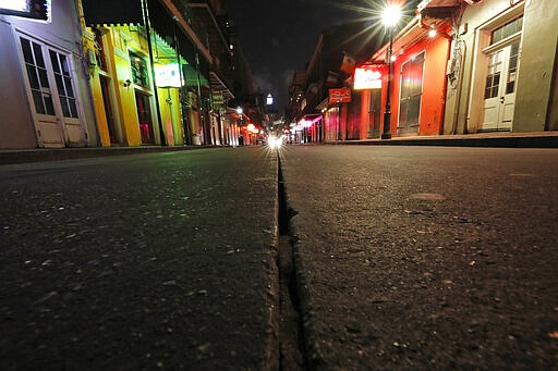 FILE - In this Thursday, March 19, 2020, file photo, a view of the nearly deserted scene on Bourbon Street, which is normally bustling with tourists and revelers, in the French Quarter of New Orleans. Like many cities around the country, New Orleans is currently under a shelter-in-place order as it grapples with a growing number of coronavirus cases. In Louisiana, Gov. John Bel Edwards has repeatedly sounded the alarm about how Louisiana has the third-highest rate of confirmed virus cases per capita while at the same time noting the difficulty of the small state getting supplies. (AP Photo/Gerald Herbert, File)