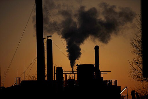 FILE - In this Friday, Dec. 14, 2018 filer, smoke billows from a chimney of a factory, in Ospiate, near Milan, Italy. The eurozone's third-largest economy and a major exporter, Italy on Wednesday becomes the first western industrialized nation to idle swaths of industrial production to stop the spread of coronavirus by keeping yet more of the population at home. The new coronavirus causes mild or moderate symptoms for most people, but for some, especially older adults and people with existing health problems, it can cause more severe illness or death. (AP Photo/Luca Bruno, File)