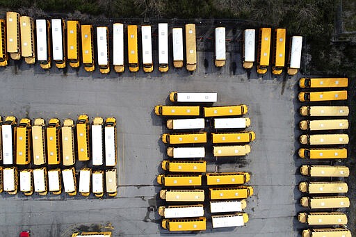 School buses sit unused in a parking lot Thursday, March 26, 2020, in St. Louis. All public and charter schools in Missouri are closed due to the coronavirus pandemic which causes mild or moderate symptoms for most people, but for some, especially older adults and people with existing health problems, it can cause more severe illness or death. (AP Photo/Jeff Roberson)