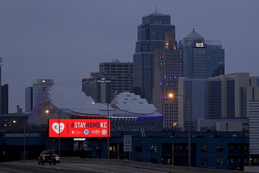 A sign urges residents to stay home as motorists drive past downtown Tuesday, March 24, 2020 on the first day of a stay-at-home order in Kansas City, Mo. Kansas City and surrounding counties instituted a 30-day mandatory stay-at-home order in an effort to stem the spread of the coronavirus. (AP Photo/Charlie Riedel)