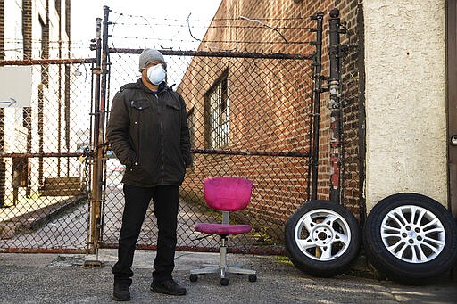 Tire shop owner M. Hernandez, wearing a protective face mask, waits for customers outside his shop in Philadelphia, Thursday, March 26, 2020. Gov. Tom Wolf&#146;s administration reported more new coronavirus-related deaths in Pennsylvania on Wednesday. Residents are ordered to stay home, with few exceptions. (AP Photo/Matt Rourke)