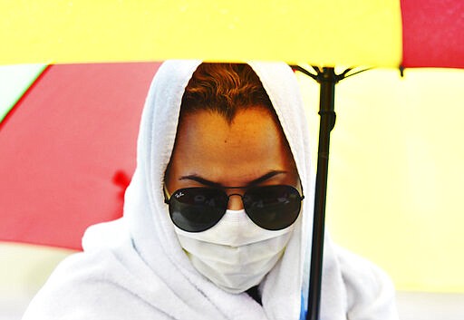 A woman, wearing a facemask to protect against the coronavirus, waits in line during an emergency food distribution at Keystone Mission in Wilkes-Barre, Pa., Wednesday, March 25, 2020. (Sean McKeag/The Citizens' Voice via AP)