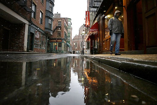 A passer-by walks down a nearly empty street in Boston's North End neighborhood, Monday, March 23, 2020. Many restaurants and businesses are closed in the ordinarily busy neighborhood out of concern about the spread of the coronavirus. (AP Photo/Steven Senne)