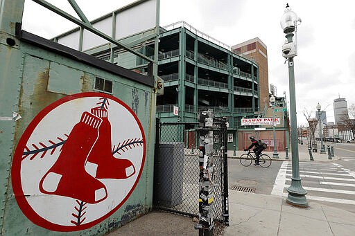 A cyclist rides past Fenway Park baseball park, Wednesday, March 25, 2020, in Boston. There will be empty ballparks on what was supposed to be Major League Baseball's opening day, with the start of the Major League Baseball regular season indefinitely on hold because of the coronavirus pandemic. (AP Photo/Steven Senne)