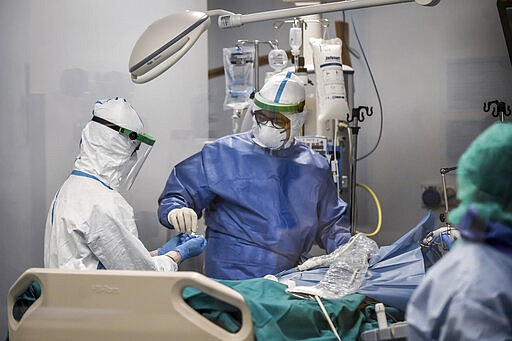 In this photograph taken from behind a window, doctors work on a Covid-19 patient in the intensive care unit of San Matteo Hospital, in Pavia, northern Italy, Thursday, March 26, 2020. The San Matteo hospital is where Patient 1, a 38-year-old Unilever worker named Mattia, was kept since he tested positive for Covid-19 on Feb. 21 and opened Italy&#146;s health care crisis. The new coronavirus causes mild or moderate symptoms for most people, but for some, especially older adults and people with existing health problems, it can cause more severe illness or death. (Claudio Furlan/LaPresse via AP)