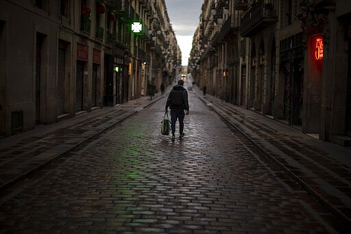 A man walks along an empty street in downtown Barcelona, Spain, Thursday, March 26, 2020 as the lockdown to combat the spread of coronavirus continues. The new coronavirus causes mild or moderate symptoms for most people, but for some, especially older adults and people with existing health problems, it can cause more severe illness or death. (AP Photo/Emilio Morenatti)