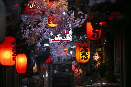 A cook wearing a mask stands outside a restaurant Thursday, March 26, 2020, in Tokyo. Japan's Prime Minister Shinzo Abe is setting up a special task force to discuss coronavirus measures and emergency responses as the government now considers the spread of the COVID-19 virus rampant in the country, officials said Thursday. (AP Photo/Jae C. Hong)