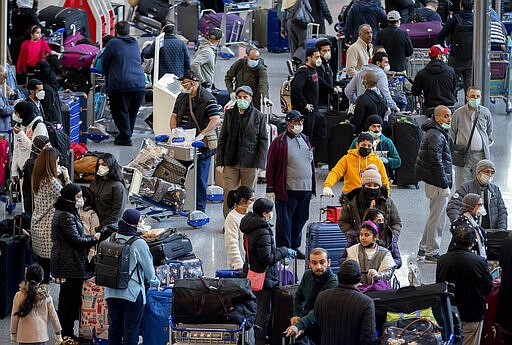 Passengers gather for a flight to Kuwait at the airport in Frankfurt, Germany, Thursday, March 26, 2020. For most people, the new coronavirus causes only mild or moderate symptoms, such as fever and cough. For some, especially older adults and people with existing health problems, it can cause more severe illness, including pneumonia. (AP Photo/Michael Probst)