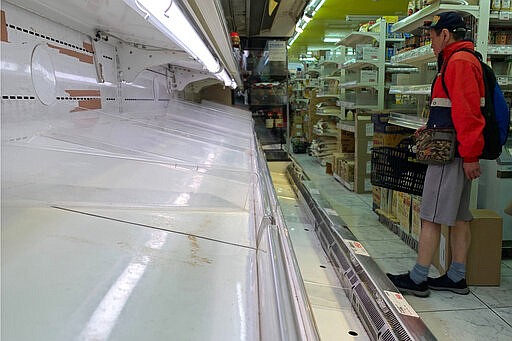 A shopper looks at empty shelf at a grocery store in Tokyo, Thursday, March 26, 2020. Residents of Tokyo on Thursday raced to stock up on foods and daily necessities after its governor on Wednesday called on residents to stay at home during this coming weekend amid rising infections of new coronavirus in the capital city.(AP Photo/Kiichiro Sato)