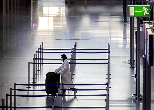 A woman walks through a terminal at the airport in Frankfurt, Germany, Thursday, March 26, 2020. For most people, the new coronavirus causes only mild or moderate symptoms, such as fever and cough. For some, especially older adults and people with existing health problems, it can cause more severe illness, including pneumonia. (AP Photo/Michael Probst)