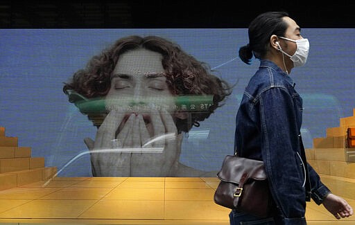 A man wearing face mask walks past a fashion shop at a downtown street in Hong Kong Thursday, March 26, 2020. For most, the coronavirus causes only mild or moderate symptoms, such as fever and cough. But for a few, especially older adults and people with existing health problems, it can cause more severe illnesses, including pneumonia. (AP Photo/Vincent Yu)