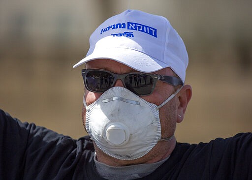 An Israeli supporter of Prime Minister Benjamin Netanyahu protests in front Israel's Supreme Court, in Jerusalem, Tuesday, March 24, 2020. Israel appeared on the verge of a constitutional crisis Tuesday as top members of Benjamin Netanyahu's Likud urged their party colleague and parliament speaker to defy a Supreme Court order to hold an election for the prime minister's successor. (AP Photo/Ariel Schalit)