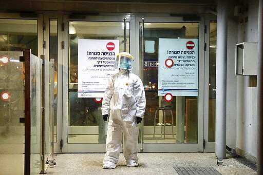 ?A municipality worker blocks the door as a firefighter sprays disinfectant as a precaution? against the coronavirus at the Moshe Dayan Railway Station in Rishon LeTsiyon, Israel, Sunday, March 22, 2020. (AP Photo/Ariel Schalit)