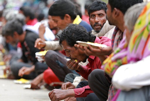 Homeless and impoverished Indians eat a meal distributed by the Delhi government in New Delhi, India, Thursday, March 26, 2020. Some of India's legions of poor and people suddenly thrown out of work by a nationwide stay-at-home order began receiving aid distribution Thursday, as both the public and private sector work to blunt the impact of efforts to curb the coronavirus pandemic. (AP Photo)