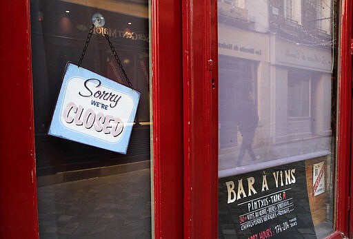 A sign hangs on the entrance door of a closed vin bar in Versailles, west of Paris, Tuesday, March 24, 2020. French President Emmanuel Macron urged employees to keep working in supermarkets, production sites and other businesses that need to keep running amid stringent restrictions of movement due to the rapid spreading of the new coronavirus in the country. For most people, the new coronavirus causes only mild or moderate symptoms, such as fever and cough. For some, especially older adults and people with existing health problems, it can cause more severe illness, including pneumonia. (AP Photo/Michel Euler)