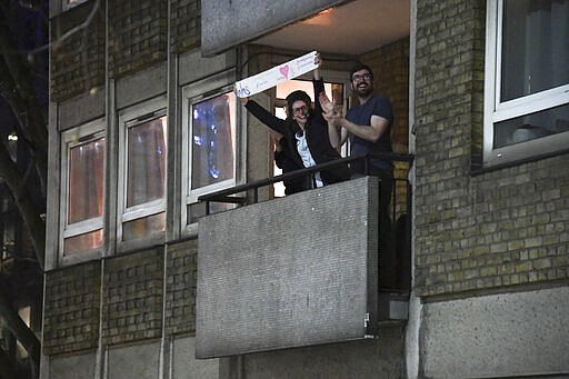 People applaud outside St. Thomas' Hospital in support of British National Health Service workers who are treating coronavirus victims, as part of a nationwide salute to the doctors, nurses and staff of the NHS in London, Thursday, March 26, 2020. The COVID-19 coronavirus pandemic has prompted a public display of appreciation for health service workers on the front line of the fight against the contagious virus. (AP Photo/Alberto Pezzali)