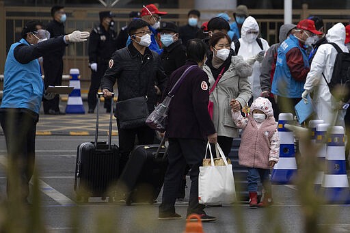 Returnees from the Hubei Province are directed by volunteers to buses waiting to disperse them to their homes upon arriving at the West Train Station in Beijing on Thursday, March 26, 2020. China is allowing people who were under lockdown in Hubei to leave the province at the center of the coronavirus outbreak now sweeping the globe. In the nation's capital, authorities are accepting about 800 people a day from Hubei. (AP Photo/Ng Han Guan)