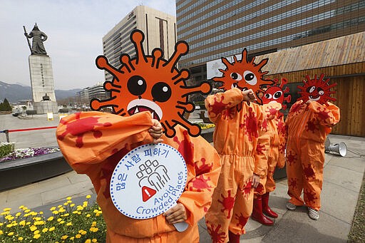 Environmental activists wearing masks symbolizing a virus perform during a new coronavirus prevention campaign in Seoul, South Korea, Thursday, March 26, 2020. For most people, the new coronavirus causes only mild or moderate symptoms, such as fever and cough. For some, especially older adults and people with existing health problems, it can cause more severe illness, including pneumonia. (AP Photo/Ahn Young-joon)