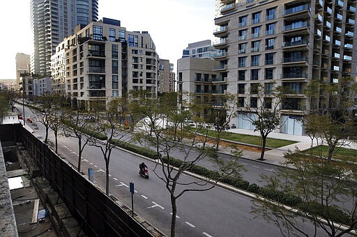 In this Monday, March 16, 2020 photo, a food deliveryman on a scooter moves on an empty street in Beirut, Lebanon. The coronavirus pandemic has managed to do what various wars could not: Close bars, restaurants and entertainment spots across the tiny Mediterranean country. (AP Photo/Bilal Hussein)