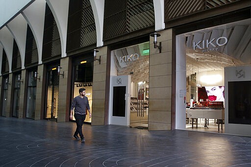 In this Monday, March 16, 2020 photo, a man walks past closed shops after authorities ordered the closure as part of the preventive measures against the preventive measures against the coronavirus, inside the upscale Beirut Souks shopping mall in Beirut, Lebanon. COVID-19 has managed to do what various wars could not: Close bars, restaurants and entertainment spots across the tiny Mediterranean country. The pandemic is an economic gut punch, delivered at a time when Lebanon is mired in the worst financial crisis in its history -- one that could hasten the country's long-feared economic collapse. (AP Photo/Bilal Hussein)