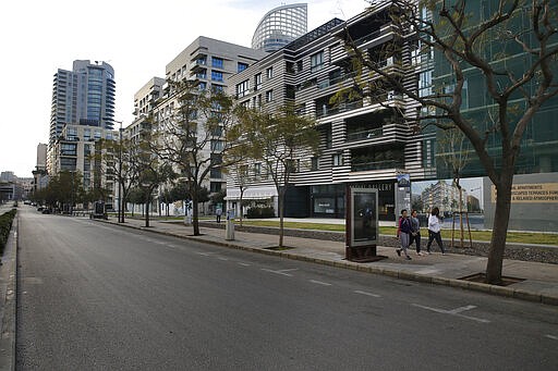 In this Monday, March 16, 2020 photo, a few people walk on an empty street in Beirut, Lebanon. The coronavirus pandemic has managed to do what various wars could not: Close bars, restaurants and entertainment spots across the tiny Mediterranean country. It's another economic gut punch, delivered at a time when Lebanon is mired in the worst financial crisis in its history -- one that could hasten the country's long-feared economic collapse. (AP Photo/Bilal Hussein)