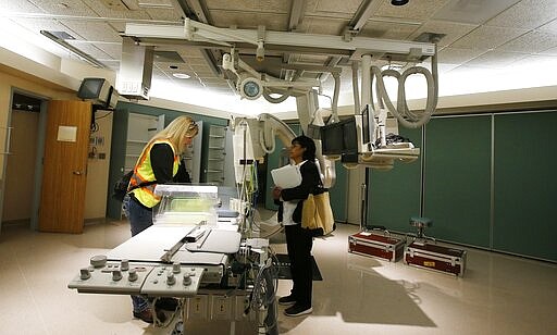 Mary Azelton, left, resident engineer of the project from the U.S. Army Corps of Engineers, and Susie McCann, from the Arizona Department of Health, tour the currently closed St. Luke's Medical Center hospital to see the viability of reopening the facility for possible future use due to the coronavirus Wednesday, March 25, 2020, in Phoenix. (AP Photo/Ross D. Franklin)