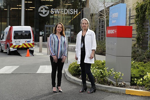 In this Tuesday, March 24, 2020, photo, Melissa Short, left, system executive director for women's health at Swedish Medical Center, and Dr. Tanya Sorensen, a practicing maternal fetal medicine physician at Swedish, and executive director for women's services, pose in front of the center in Edmonds, Wash., north of Seattle. Several dozen expectant moms who had planned to give birth at the birth unit of the center will now have to go elsewhere because the facility is being repurposed to treat victims of the new coronavirus. (AP Photo/Ted S. Warren)