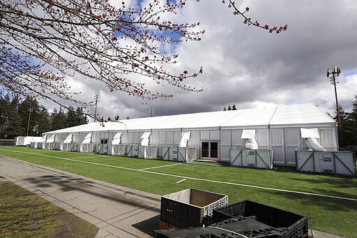 In this photo taken Tuesday, March 24, 2020, one of a pair of massive temporary buildings meant for use as a field hospital for coronavirus patients stands on a soccer field in the Seattle suburb of Shoreline, Wash. With U.S. hospital capacity stretched thin, hospitals around the country are scrambling to find space for a coming flood of COVID-19 patients, opening older closed hospitals and repurposing other buildings. (AP Photo/Elaine Thompson)