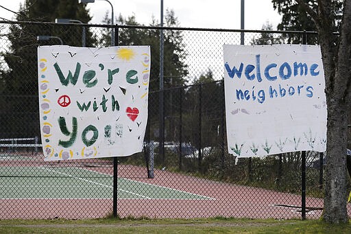 In this photo taken Tuesday, March 24, 2020, handmade signs posted to a tennis court fence are set to greet future patients at a temporary field hospital for coronavirus patients on an adjacent soccer field in the Seattle suburb of Shoreline, Wash. With U.S. hospital capacity stretched thin, hospitals around the country are scrambling to find space for a coming flood of COVID-19 patients, opening older closed hospitals and repurposing other buildings. (AP Photo/Elaine Thompson)