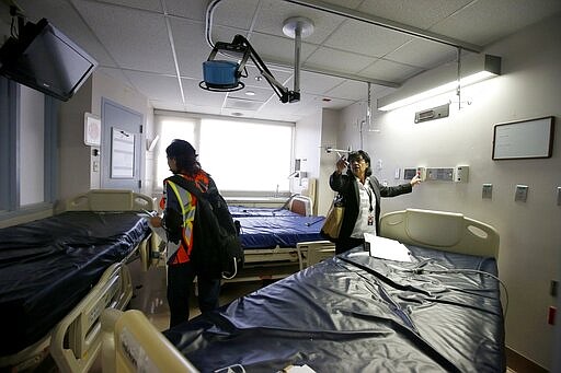 Susie McCann, right, of the Arizona health department, assess a room in the emergency area with a member of the U.S. Army Corps of Engineers as they tour the currently closed St. Luke's Medical Center hospital to see the viability of reopening the facility for possible future use due to the coronavirus Wednesday, March 25, 2020, in Phoenix. (AP Photo/Ross D. Franklin)