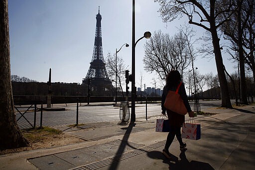 A woman walks in an empty street near the Eiffel Tower during a nationwide confinement to counter the new coronavirus, in Paris, Thursday, March 26, 2020. The new coronavirus causes mild or moderate symptoms for most people, but for some, especially older adults and people with existing health problems, it can cause more severe illness or death. (AP Photo/Thibault Camus)