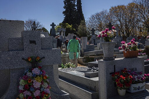 An undertaker wearing a garbage bag atop of a gown as a safety mesure during the coronavirus outbreak works at cemetery in Madrid, Spain, Thursday, March 25, 2020. The new coronavirus causes mild or moderate symptoms for most people, but for some, especially older adults and people with existing health problems, it can cause more severe illness or death. (AP Photo/Bernat Armangue)