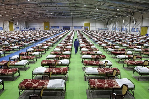 A member of the Iranian army walks past rows of beds at a temporary 2,000-bed hospital for COVID-19 coronavirus patients set up by the army at the international exhibition center in northern Tehran, Iran, on Thursday, March 26, 2020. (AP Photo/Ebrahim Noroozi)