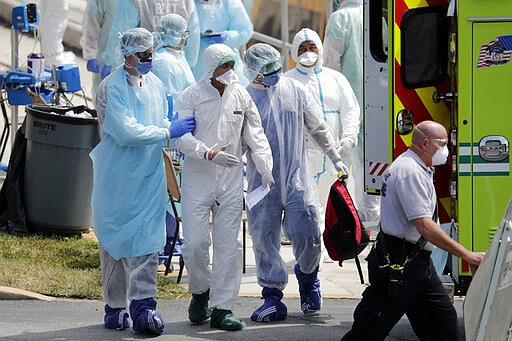 An ill crew member from the Costa cruise ship Favolosa, second from left, is led to a waiting ambulance after being brought ashore in a lifeboat during the coronavirus outbreak to the U.S. Coast Guard Base Miami Beach, Thursday, March 26, 2020, in Miami Beach, Fla. Miami-area hospitals received crew members Thursday from two Costa Cruise ships, the Magica and Favolosa. Carnival Corp., which owns the cruise line, said the ships are empty except for crew members. (AP Photo/Lynne Sladky)