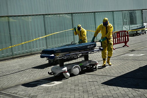 Volunteer workers of a regional search and rescue move a stretcher, close to Navarra Hospital, in Pamplona, northern Spain, Thursday, March 26, 2020. The new coronavirus causes mild or moderate symptoms for most people, but for some, especially older adults and people with existing health problems, it can cause more severe illness or death. (AP Photo/Alvaro Barrientos)