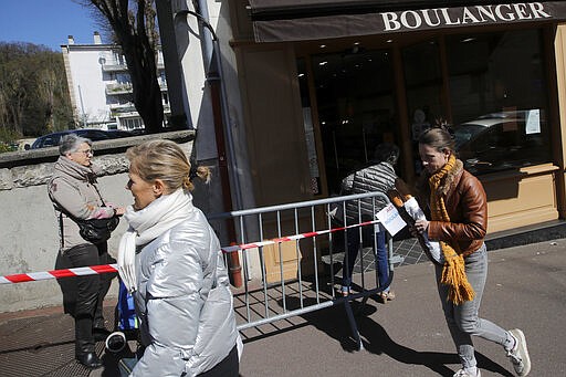 Customers queue to buy bread in a Ville d'Avray bakery, outside Paris, Tuesday, March 24, 2020. French President Emmanuel Macron urged employees to keep working in supermarkets, production sites and other businesses that need to keep running amid stringent restrictions of movement due to the rapid spreading of the new coronavirus in the country. For most people, the new coronavirus causes only mild or moderate symptoms. For some it can cause more severe illness, especially in older adults and people with existing health problems. (AP Photo/Christophe Ena)