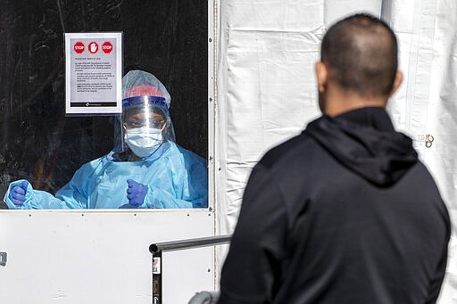 A member of the Brooklyn Hospital Center COVID-19 testing team calls in the next patient in line, Thursday, March 26, 2020, in the Brooklyn borough of New York. The new coronavirus causes mild or moderate symptoms for most people, but for some, especially older adults and people with existing health problems, it can cause more severe illness or death. (AP Photo/Mary Altaffer)