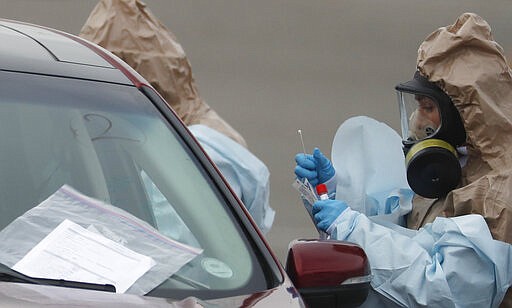 Colorado National Guard medical personnel perform coronavirus test on a motorist at a drive-thru testing site outside the Denver Coliseum Saturday, March 14, 2020, in Denver. Officials planned to administer 150 tests but the line of vehicles wrapped around three city blocks. For most people, the new coronavirus causes only mild or moderate symptoms. For some it can cause more severe illness.(AP Photo/David Zalubowski)