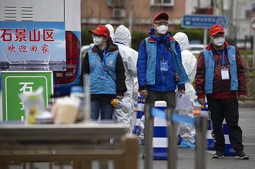 Volunteers wait to escort returnees from the Hubei Province arriving at the West Train Station in Beijing on Thursday, March 26, 2020. China is allowing people who were under lockdown in Hubei to leave the province at the center of the coronavirus outbreak now sweeping the globe. In the nation's capital, authorities are accepting about 800 people a day from Hubei. (AP Photo/Ng Han Guan)