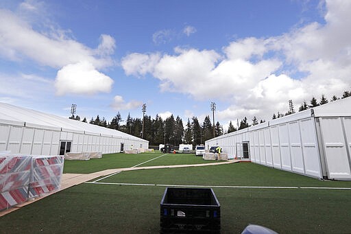 In this photo taken Tuesday, March 24, 2020, two massive temporary buildings meant for use as a field hospital for coronavirus patients stand together on a soccer field in the Seattle suburb of Shoreline, Wash. With U.S. hospital capacity stretched thin, hospitals around the country are scrambling to find space for a coming flood of COVID-19 patients, opening older closed hospitals and repurposing other buildings. (AP Photo/Elaine Thompson)