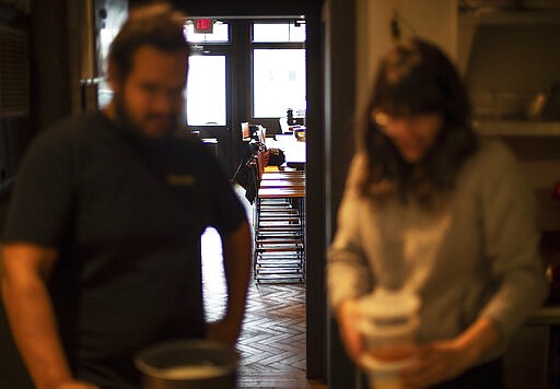 Empty stools stand in the background as James Mark, left, owner of the restaurant Big King, talks with Jennifer Wittlin as they prepare for dinner takeout orders Wednesday, March 25, 2020, in Providence, R.I. Mark said pushing to restart the economy before the health crisis is over would put businesses like his in a terrible position. As things are now, there's some leverage for small businesses to negotiate with landlords or banks over rents, mortgages and debt payments. &quot;I don't think there's any economic solution until the health side of this gets solved,&quot; Mark said. &quot;We can't rush this.&quot; (AP Photo/David Goldman)