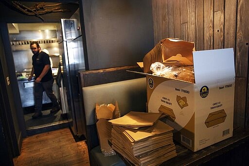 Take-out supplies sit on a table as James Mark, owner of the restaurant Big King, prepares for dinner take-out orders Wednesday, March 25, 2020, in Providence, R.I. Mark said pushing to restart the economy before the health crisis is over would put businesses like his in a terrible position. As things are now, there's some leverage for small businesses to negotiate with landlords or banks over rents, mortgages and debt payments. &quot;I don't think there's any economic solution until the health side of this gets solved,&quot; Mark said. &quot;We can't rush this.&quot; (AP Photo/David Goldman)