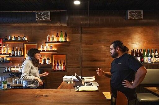 James Mark, right, owner of the restaurant Big King, talks with Jennifer Wittlin as they prepare for dinner take-out orders Wednesday, March 25, 2020, in Providence, R.I. Mark said pushing to restart the economy before the health crisis is over would put businesses like his in a terrible position. As things are now, there's some leverage for small businesses to negotiate with landlords or banks over rents, mortgages and debt payments. &quot;I don't think there's any economic solution until the health side of this gets solved,&quot; Mark said. &quot;We can't rush this.&quot; (AP Photo/David Goldman)