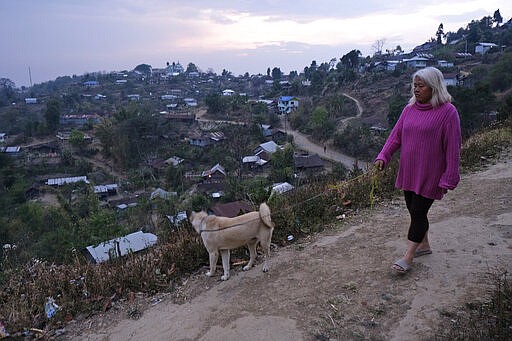 FILE- In this Sunday, March 22, 2020, file photo, a woman walks her dog, as most people in this mountain village stayed indoors with fears of a rumor of medicine being sprayed from the sky to contain the new virus, in Shangshak village, in the northeastern Indian state of Manipur. As South Asian nations, including India, brace for the likely spread of the virus, they are facing another battle: reams of misinformation, misleading rumors and false claims. This battle has been hard to contain as social media continues to be rife with bogus remedies to tales of magic cure and potentially dangerous medical advice. (AP Photo/Yirmiyan Arthur)