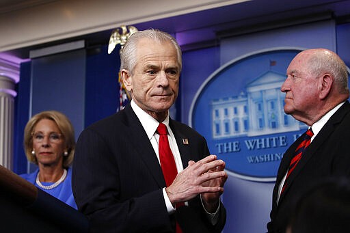 White House trade adviser Peter Navarro, who will now serve as national defense production act policy coordinator, walks from the podium after speak about the coronavirus in the James Brady Press Briefing Room, Friday, March 27, 2020, in Washington. Watching as Education Secretary Betsy DeVos and Agriculture Secretary Sonny Perdue watch. (AP Photo/Alex Brandon)