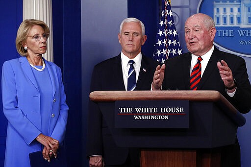 Agriculture Secretary Sonny Perdue speaks about the coronavirus in the James Brady Press Briefing Room, Friday, March 27, 2020, in Washington, as Education Secretary Betsy DeVos and Vice President Mike Pence listen. (AP Photo/Alex Brandon)