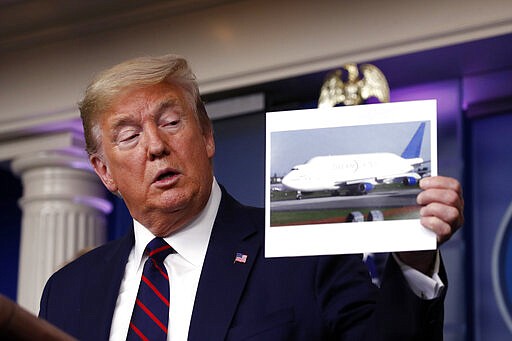 President Donald Trump holds up a photo of a Boeing Dreamlifter cargo airplane as he speaks about the coronavirus in the James Brady Press Briefing Room, Friday, March 27, 2020, in Washington. (AP Photo/Alex Brandon)