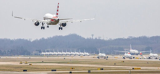 An American Airlines plane lands near dozens of parked American Airlines planes at the Pittsburgh International Airport Friday, March 27, 2020, in Moon, Pa. The airport has become a parking destination for the airline during the COVID-19 shutdown. (Andrew Rush/Pittsburgh Post-Gazette via AP)